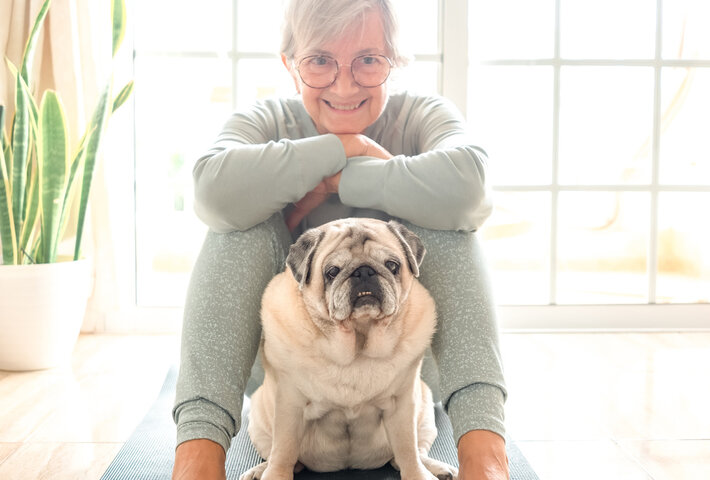 older woman with a therapy dog doing yoga