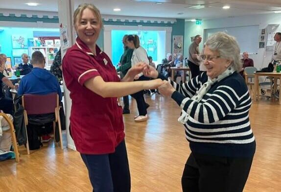 resident dancing in lounge with care assistant