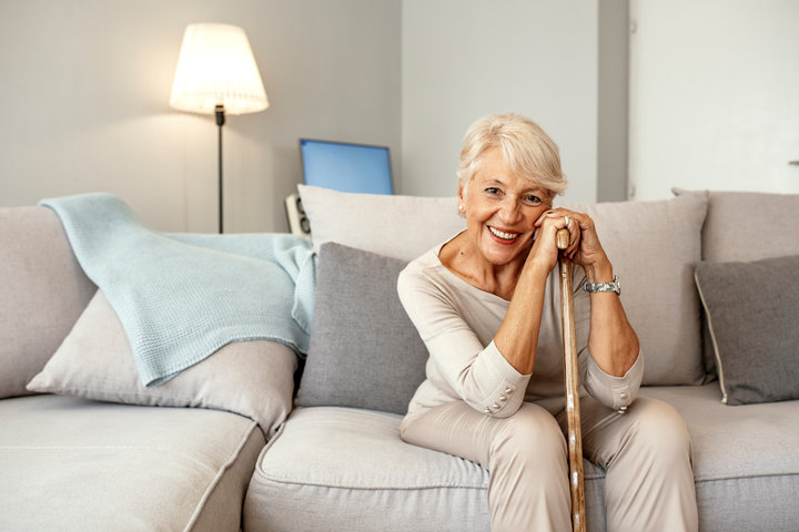 senior woman smiling in a care home with a waking stick