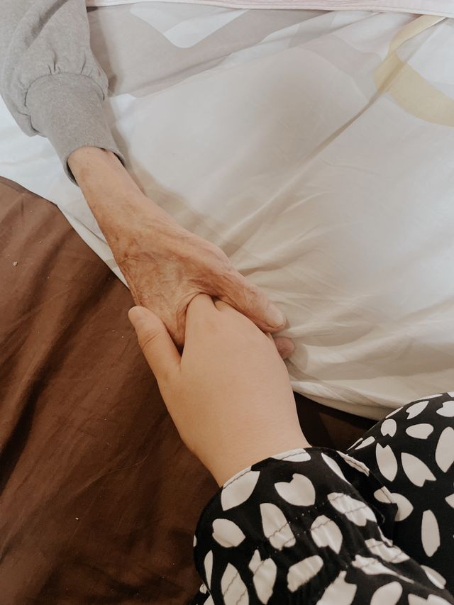 people holding hands of loved one in end of life care